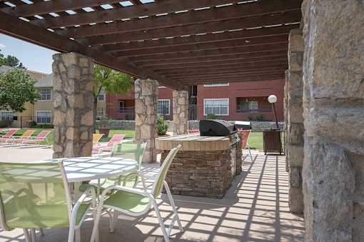 A patio with a table and chairs under a wooden pergola.