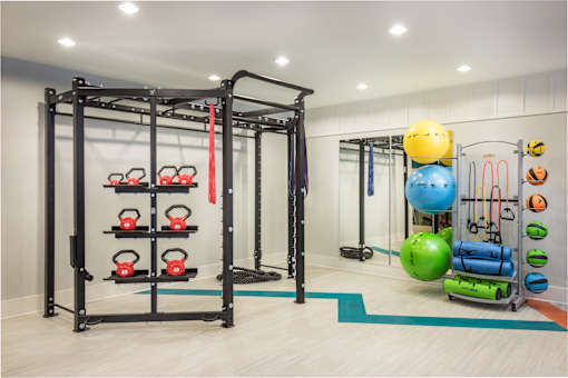 A gym with a weight rack, kettlebells, and exercise balls.