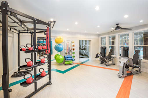 A fitness center gym with a variety of equipment including a weight rack, exercise balls, and a treadmill.
