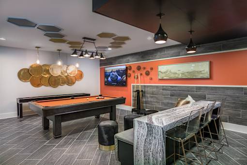 A room with a pool table and a TV on the wall.