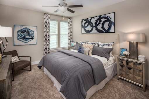 A bedroom with a large bed and a ceiling fan.