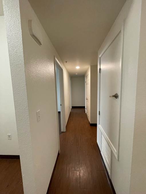 A long hallway with white walls and wood floors.