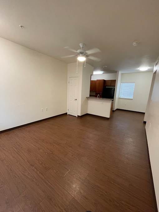 A room with a ceiling fan and wooden flooring.