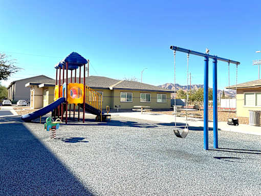 A playground with a blue swing set and a yellow slide.