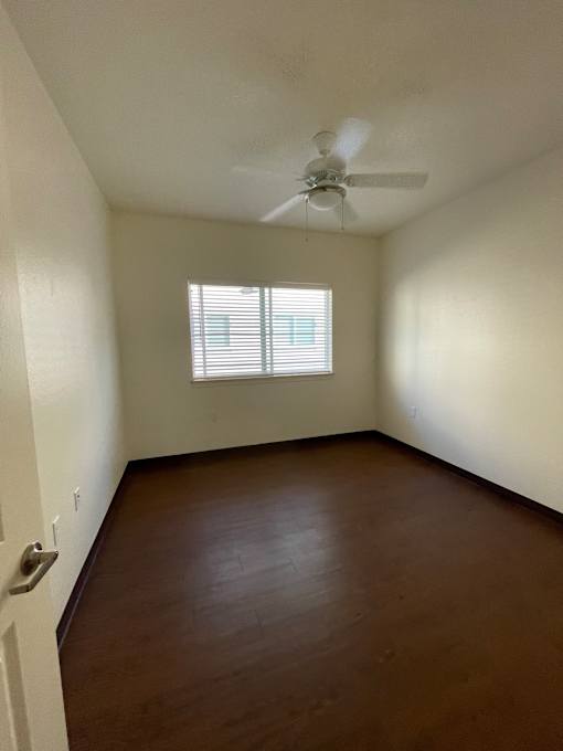 A room with a ceiling fan and a window with blinds.