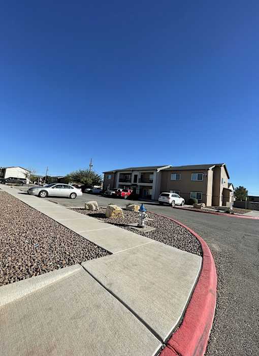 A residential area with a curved sidewalk and a building in the background.