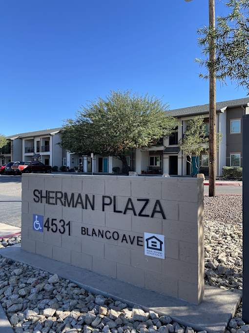 A sign for Sherman Plaza stands in front of a building.