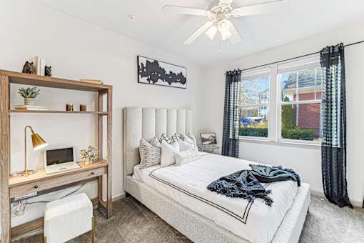 A bedroom with a bed, desk, and window.