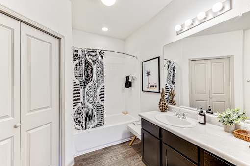 A bathroom with a white tub, sink, and shower curtain.