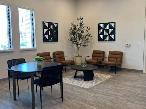A room with a table, chairs and two pictures on the wall.