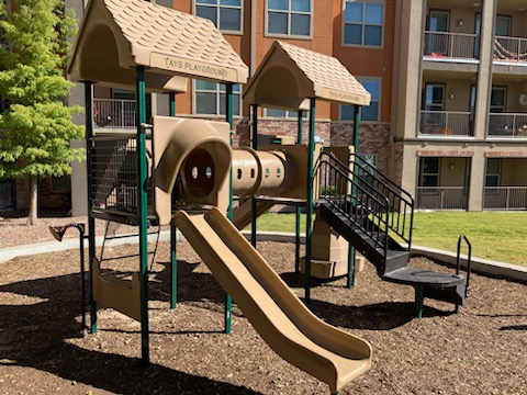 A playground with a slide and a playhouse.