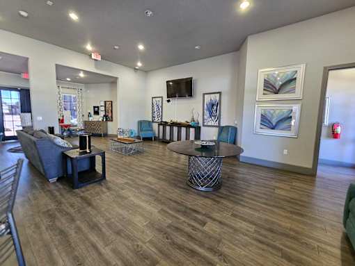 A spacious living room with a dark wood floor and furniture.