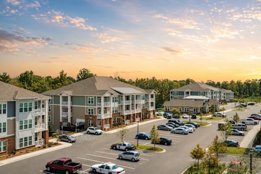 A parking lot with cars and apartment buildings in the background.