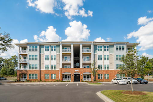 A large apartment building with a parking lot in front.