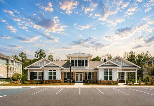 A large white building with a black roof and a parking lot in front.