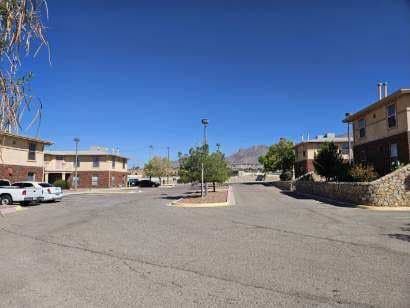 A parking lot with a few cars and buildings in the background.