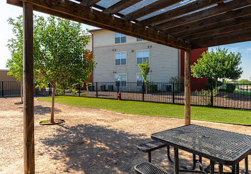 A wooden pergola over a picnic table in a park.