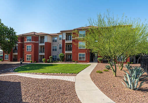 Apartment complex with a red brick building and a sidewalk.