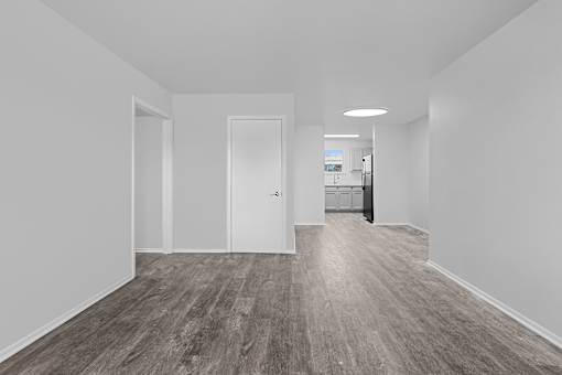 A long hallway with wood floors and white walls.