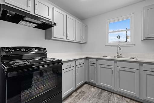 A kitchen with a black stove top oven and white cabinets.