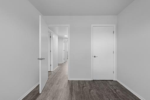 A long hallway with white doors and wood floors.