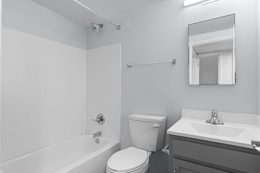A white bathroom with a toilet, sink, and bathtub.