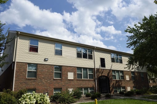 the exterior of a brick apartment building with a cloudy blue sky