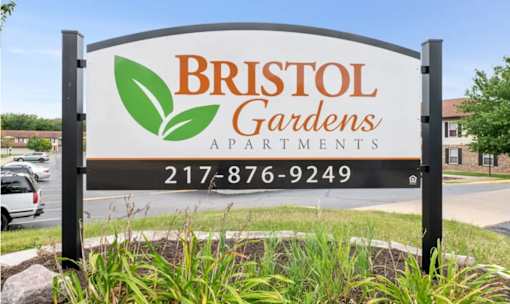 A sign for Bristol Gardens Apartments with a phone number on it.