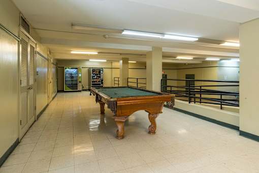 A pool table in a room with a white floor and walls.