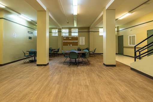 A room with wooden floors and a staircase on the right side.