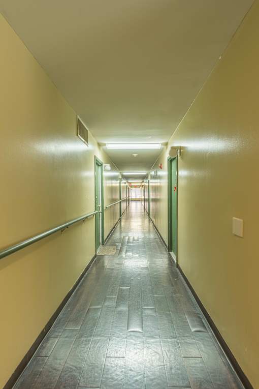 A long hallway with yellow walls and green doors.