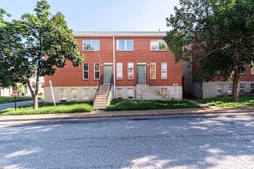 A red brick building with a tree in front of it.
