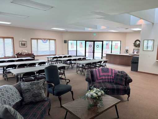 A room with tables and chairs and a couch with a blanket on it.