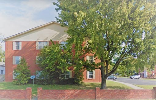 a red brick house with a tree in front of it