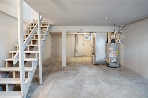 A room with a staircase and a furnace.