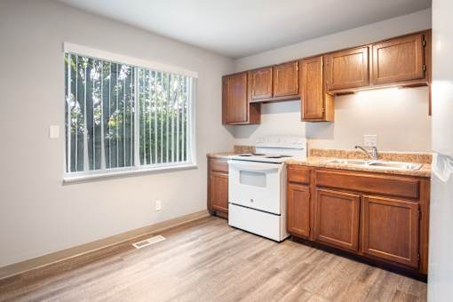 A kitchen with wooden cabinets and a white stove top oven.