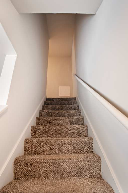 A staircase with a carpeted runner and white walls.