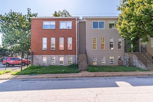 Two houses side by side with a red car parked in front of the brick house.