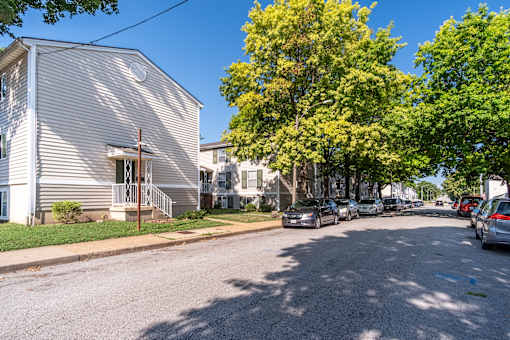 A residential street with houses and parked cars.