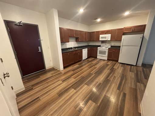A kitchen with wooden floors and white appliances.