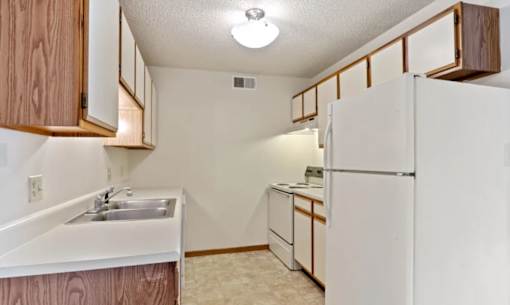 A kitchen with white appliances and wooden cabinets.