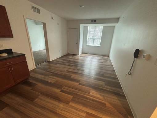 A room with wooden flooring and a phone on the wall.