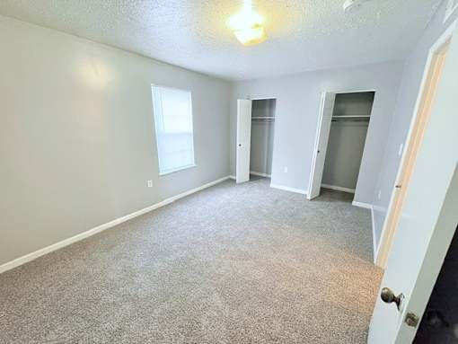 A room with a carpeted floor and a door on the right side.