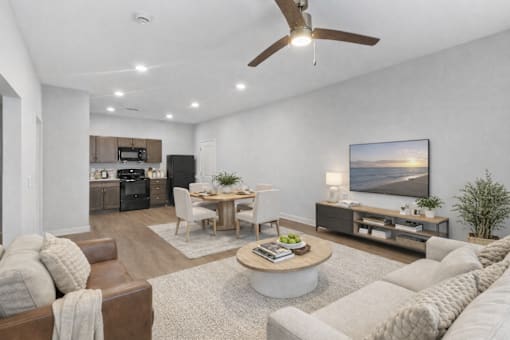 A living room with a brown leather couch, a white couch, a wooden coffee table, and a flat screen TV mounted on the wall.
