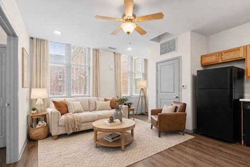 A living room with a black refrigerator and a brown armchair.