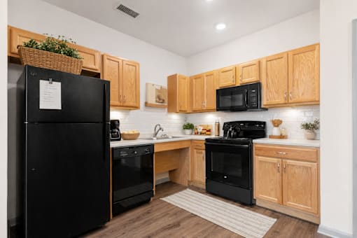 A kitchen with black appliances and wooden cabinets.