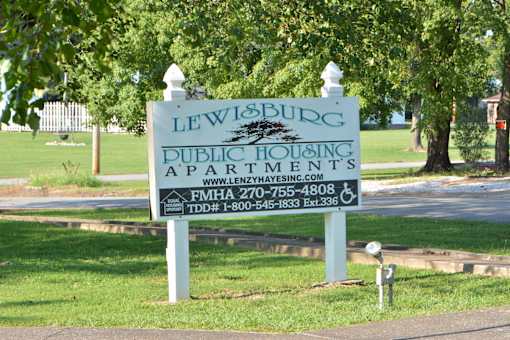 a sign for lewisburg public housing apartments in a park