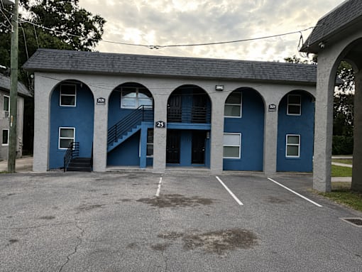 A blue building with arched windows and a staircase.