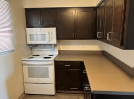 A kitchen with a white stove and black cabinets.
