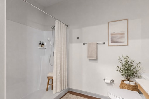 A white bathroom with a shower curtain and a plant on the toilet.